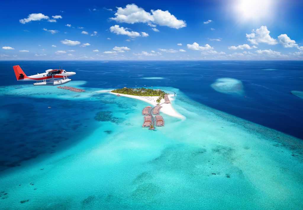 Exotic travel concept with a aerial view of a seaplane approaching a tropical paradise island